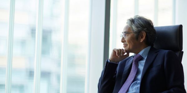 executive leader looking out the office window with a hopeful smirk