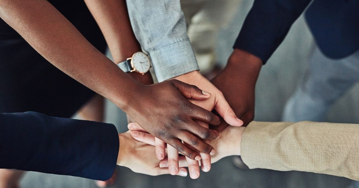 Diverse hands stacked together in a circle, symbolizing teamwork and unity